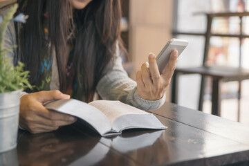 Beautiful woman (christian) hands on bible.She sending message and shopping online by smartphone.Asian serious woman reading books for exam in library.Study and technology concept.