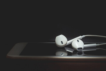 Earphones and smart phone on wooden table., Black and white tone.