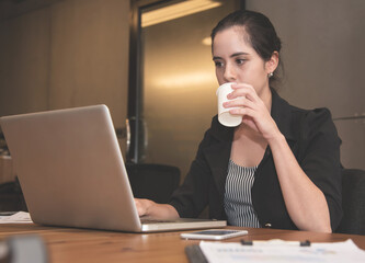 Businesswoman drinking water while working with laptop  at the office.