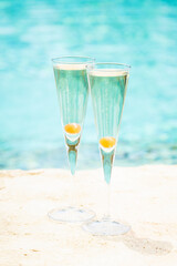 Two glasses of prosecco cocktail with orange berry at the edge of a resort pool. Concept of luxury vacation