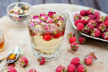 Herbal tea with rose buds and fresh raspberry.