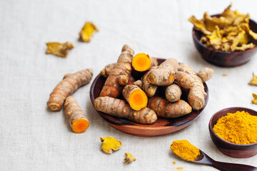 Fresh and dried turmeric roots in a wooden bowl.