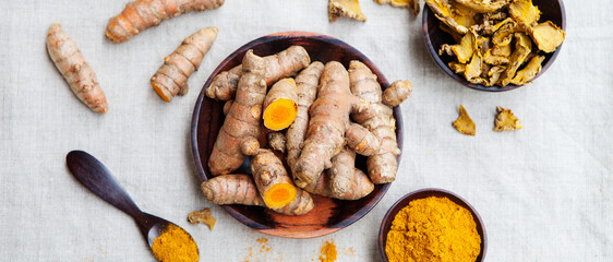 Fresh and dried turmeric roots in a wooden bowl