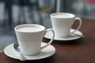 Hot Cappuccino - Closeup of a cup of coffee with milk on wooden table and blurred background, Morning Breakfast.