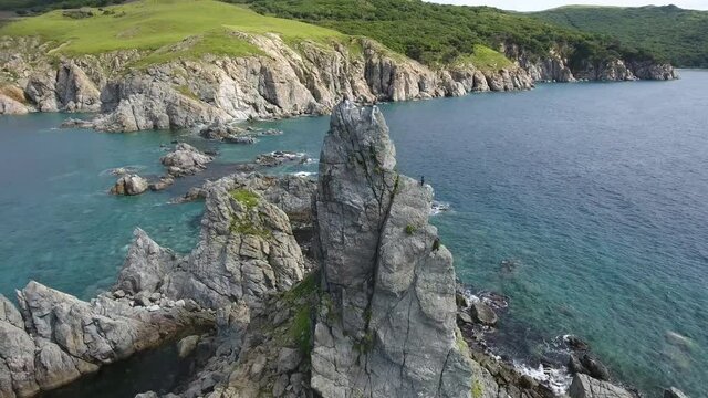 Flight around large kelura standing rock in the sea. Cliff with birds. Far East marine reserve. Vladivostok unique national Park best Russia nature. Stormy dark clouds. Epic cinematic aerial drone 4k
