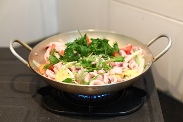 Happy housewife cooking squid with seafood in home kitchen