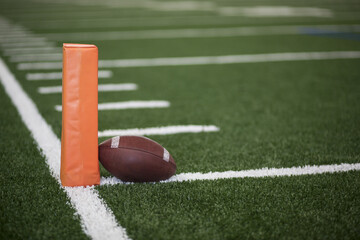 Ball resting on the goal line of a Football field endzone next to an orange pylon
