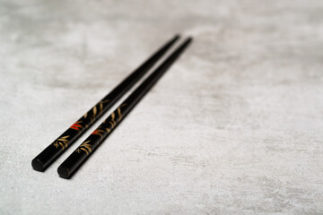Fototapeta na wymiar Black chopsticks on concrete background with selective focus