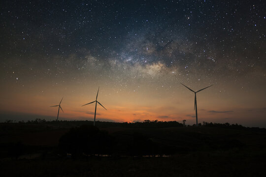 Fototapeta Milky way galaxy over wind turbine clean energy