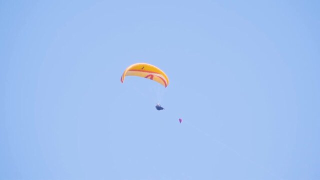 man is flying on a paraglider against the blue sky.