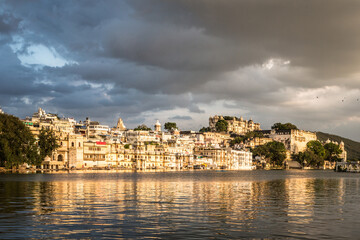 Obraz premium Sunset over lake Pichola with Udaipur old town lakefront and the City Palace in Rajasthan, India