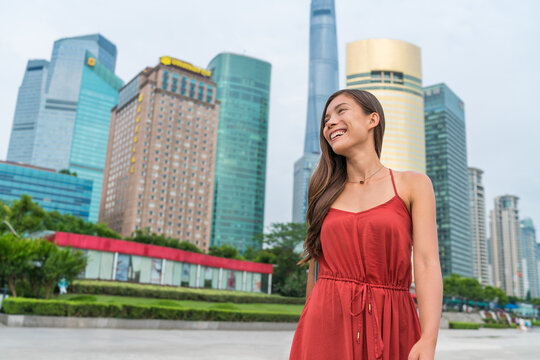 Shanghai woman walking in Pudong by huangpu river with view of the business district. Tourist or casual girl in beautiful red dress enjoying walk at Pudong boardwalk.