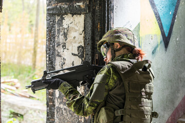 Portrait of armed woman with camouflage. Young female soldier observe with firearm. Child soldier...