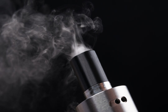 Top of an electronic cigarette with smoke on a black background