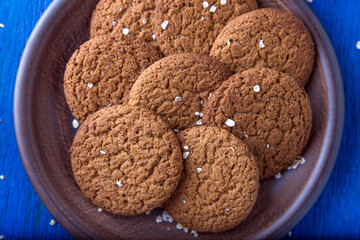 Oatmeal cookies in brown plate on blue background. Rustic style. Top view