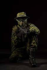 Portrait of armed woman with camouflage. Young female airsoft sniper observe with firearm. Soldier with gun in war, black background.  Military, army people concept