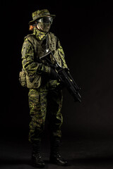 Portrait of armed woman with camouflage. Young female airsoft sniper observe with firearm. Soldier with gun in war, black background.  Military, army people concept