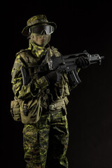Portrait of armed woman with camouflage. Young female airsoft sniper observe with firearm. Soldier...