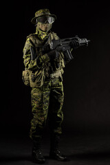 Portrait of armed woman with camouflage. Young female airsoft sniper observe with firearm. Soldier with gun in war, black background.  Military, army people concept