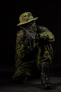 Portrait of armed woman with camouflage. Young female airsoft sniper observe with firearm. Soldier with gun in war, black background.  Military, army people concept