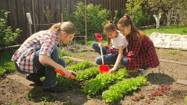 4K footage of young woman teaching her daughters in backyard garden