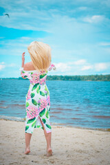 A beautiful european girl with a figure and the right features in a dress with a floral princess resting on the weekend enjoying the sun and a beautiful view of the water