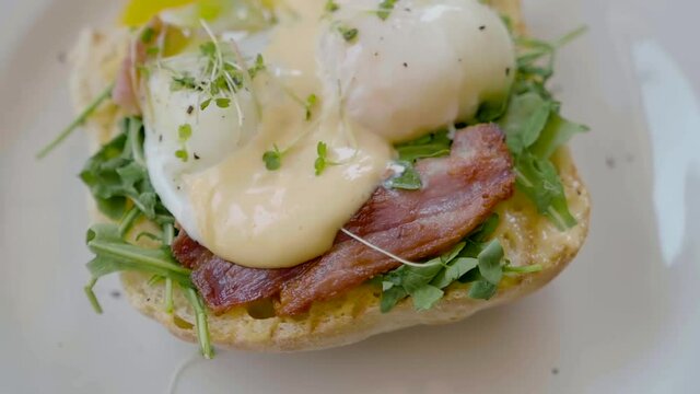 Eggs Benedict with bread and tomato on a plate with becon morning sandwich