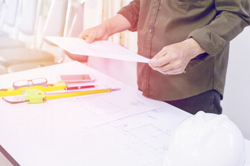 blurred male hand holding a paper engineers and technicians with tools, light Sunset.