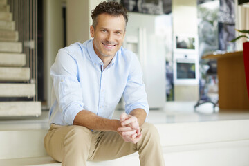 Enjoy my life. Shot of a handsome smiling man relaxing his modern home. 