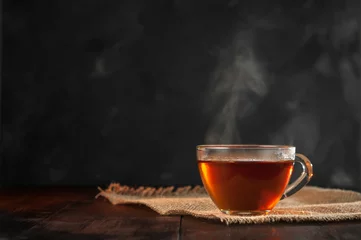 Photo sur Plexiglas Theé Une tasse de thé noir fraîchement infusé, s& 39 échappant de vapeur, lumière douce et chaude, fond plus sombre.