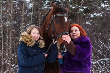 Teenager girl, mom and horse in a winter