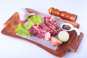 Raw beef edges, lettuce leaf, garlic, pepper grinder and spices on wooden desk isolated on white background from above and copy space. ready for cooking.