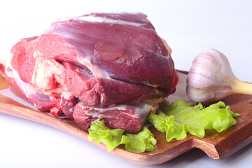 Raw beef shanks, garlic and lettuce leaf on wooden desk isolated on white background from above and copy space. ready for cooking.