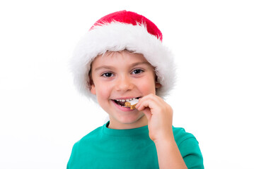Kleiner Junge mit Weihnachtsmann-Mütze isst ein plätzchen