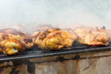 Chicken kebab prepared in a rusty brazier. In the background smoke.