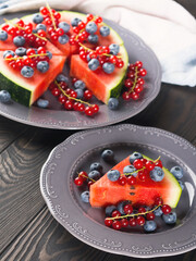 Slice of watermelon served as cake or pizza with fresh berries on rustic background