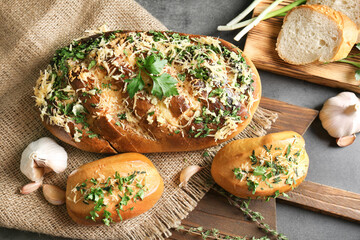 Tasty bread with grated cheese, garlic and herbs on cutting board