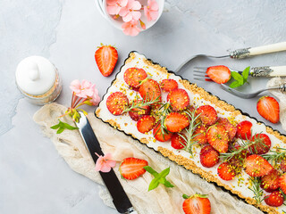 Home made strawberry not baked cheese cake in oven tin on gray background with flowers