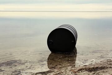 Big black barrel on beach. Environment pollution concept