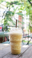 Coffee smoothie on a wooden table and plant background.