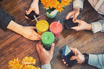 People's arms, smartphones and  vegetarian juice.