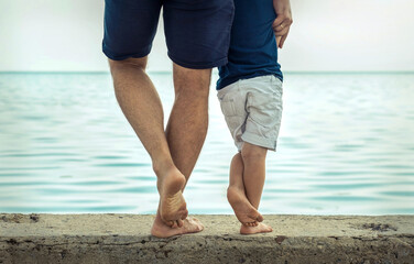 Father and son stay on the sea beach under sunlight at summer ti