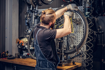 Mechanic repairing bicycle wheel tire in a workshop.