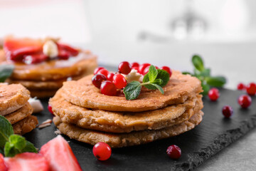 Stack of delicious coconut pancakes with berries and mint on slate plate, close up