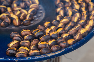 Fried chestnuts on the street. Street food. Roasted chestnuts served in a special perforated chestnut pan.