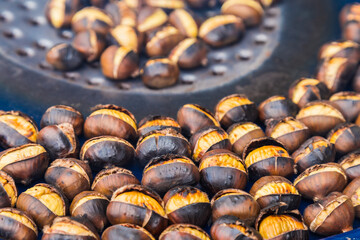 Fried chestnuts on the street. Street food. Roasted chestnuts served in a special perforated chestnut pan.