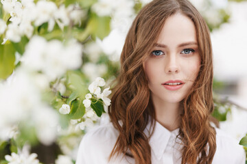 Fototapeta premium Portrait of young beautiful woman on green flower background in summer