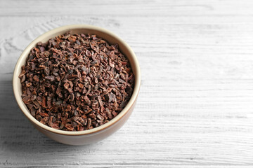 Bowl with cocoa nibs on wooden background