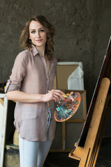 Portrait of a young woman with oil paint in art studio