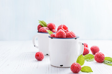 Fresh raspberries in  white ceramic mugs, with copy space. Selective focus.
